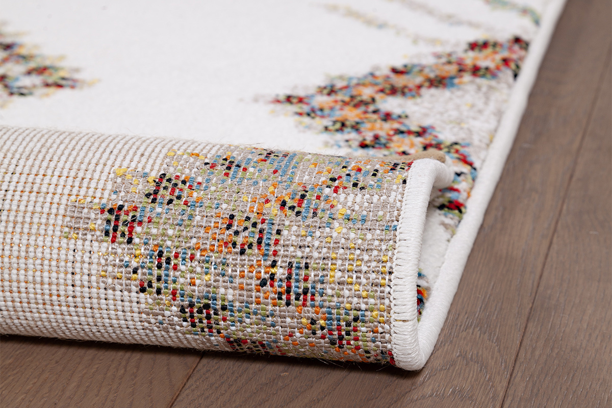 Vista cercana del borde de una alfombra de motivos coloridos sobre parqu.