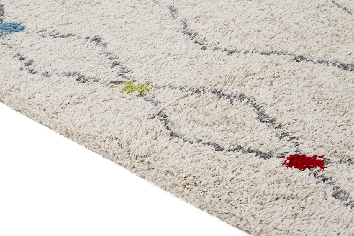 Alfombra beige rectangular con motivos de rombos y toques de color, vista lateral.