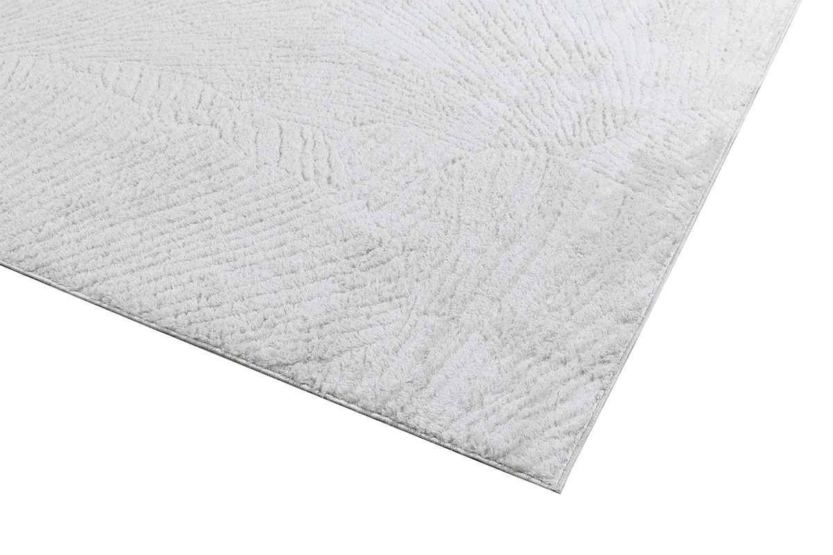 Alfombra rectangular marfil con motivos, vista en detalle con textura en el borde.