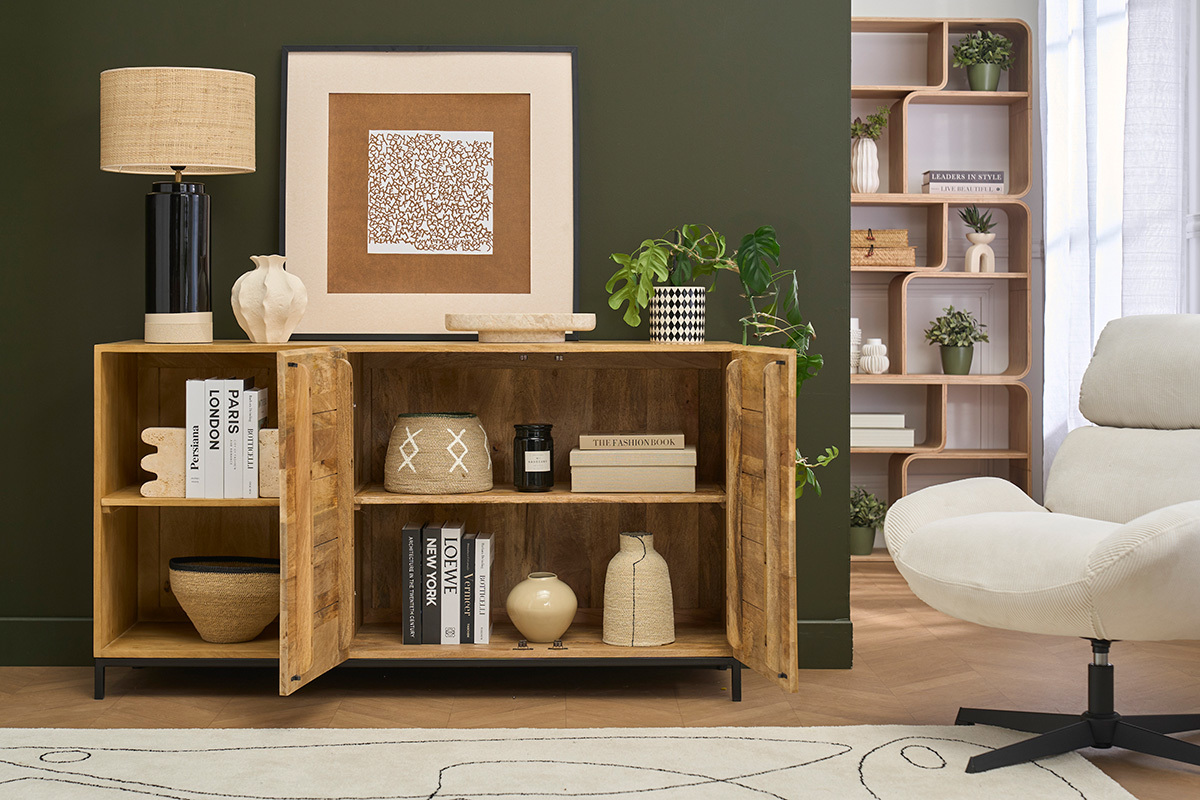 Buffet industrial en madera de mango y metal negro, abierto con objetos decorativos visibles, sobre fondo verde.