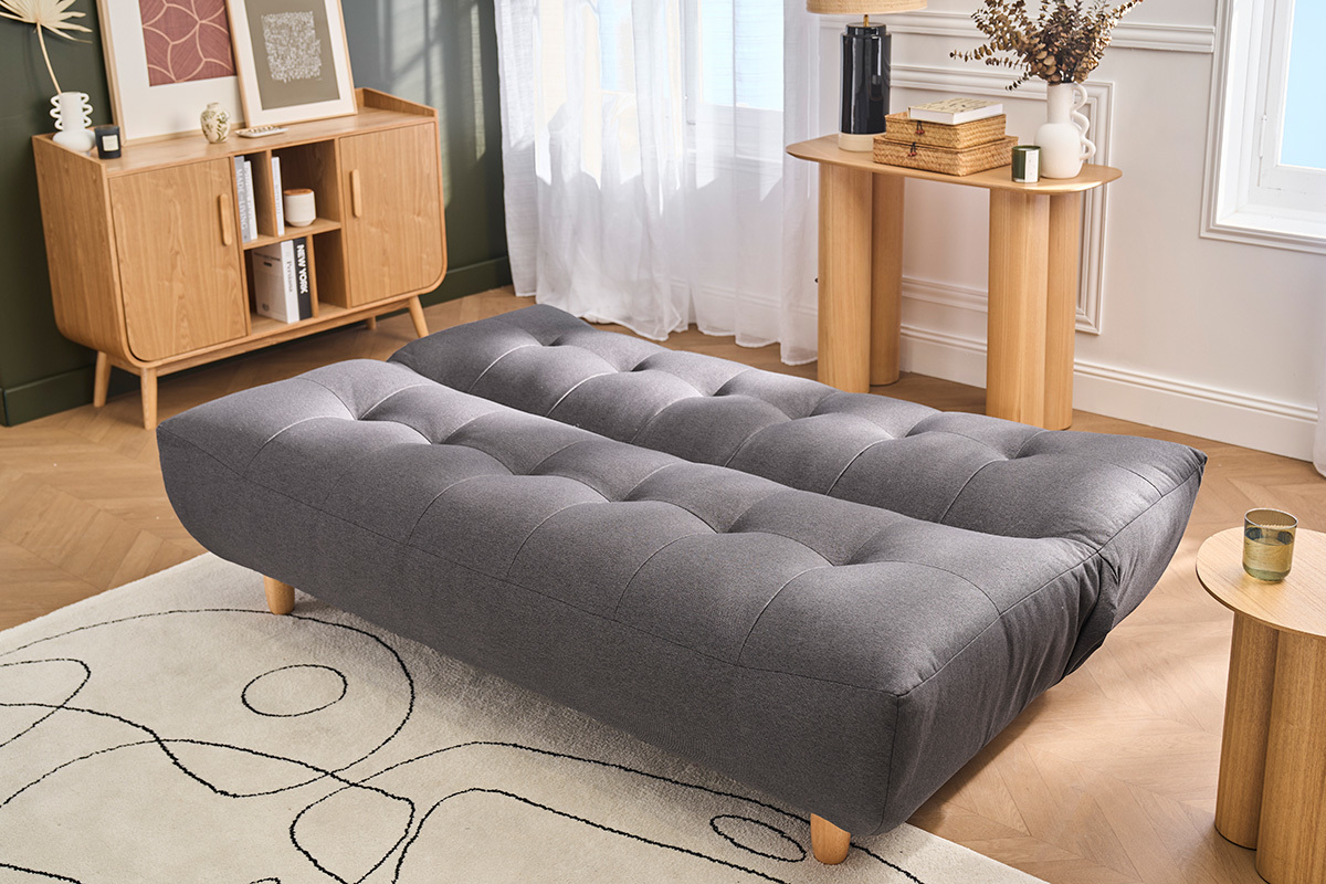 Sof� cama escandinavo en gris oscuro YUMI desplegado, con patas de madera clara, en una sala de estar.