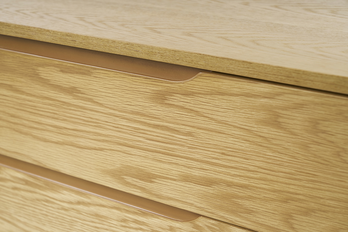 Primer plano del tocador escandinavo de madera clara con tiradores integrados.