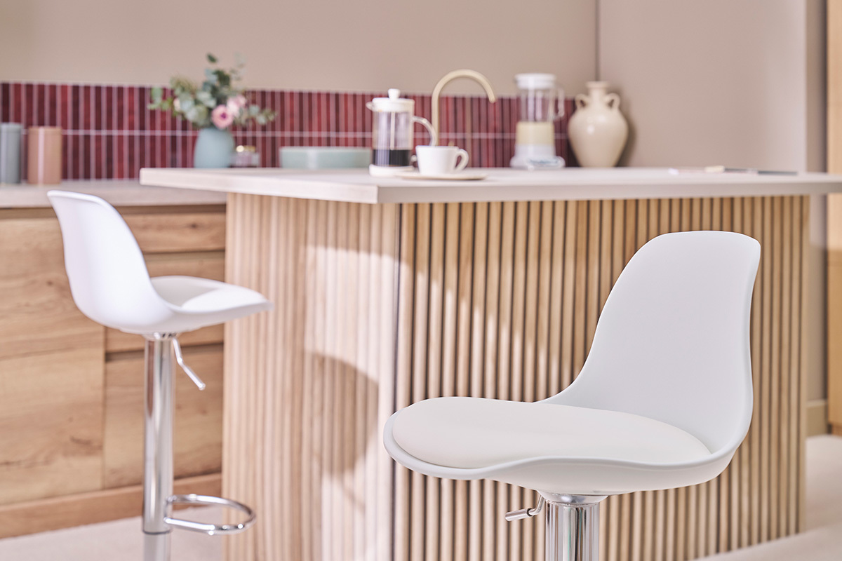 Taburetes de bar blancos de dise�o STEEVY frente a una isla de cocina moderna.