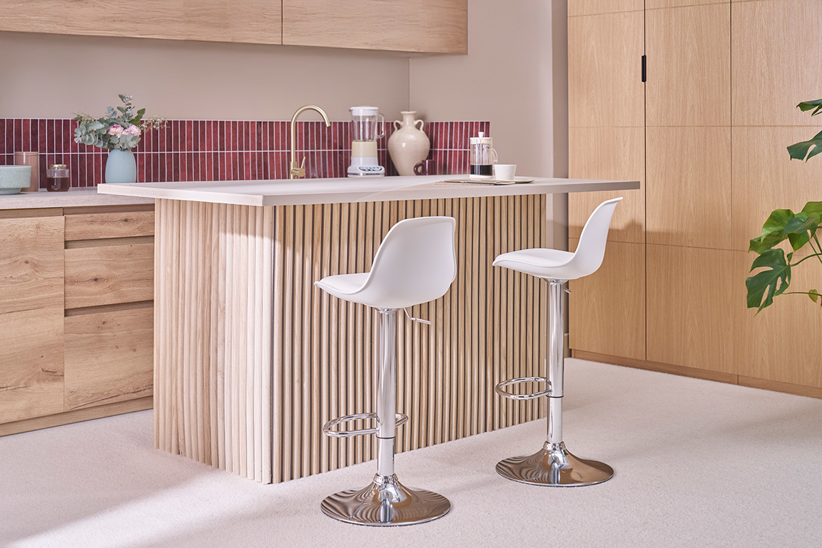 Taburetes de bar blancos con pie cromado, vista lateral en una cocina moderna.
