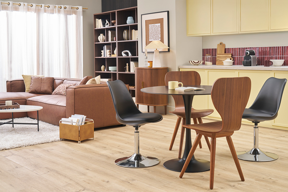 Sillas vintage de madera oscura de nogal alrededor de una mesa redonda negra en una sala de estar moderna.