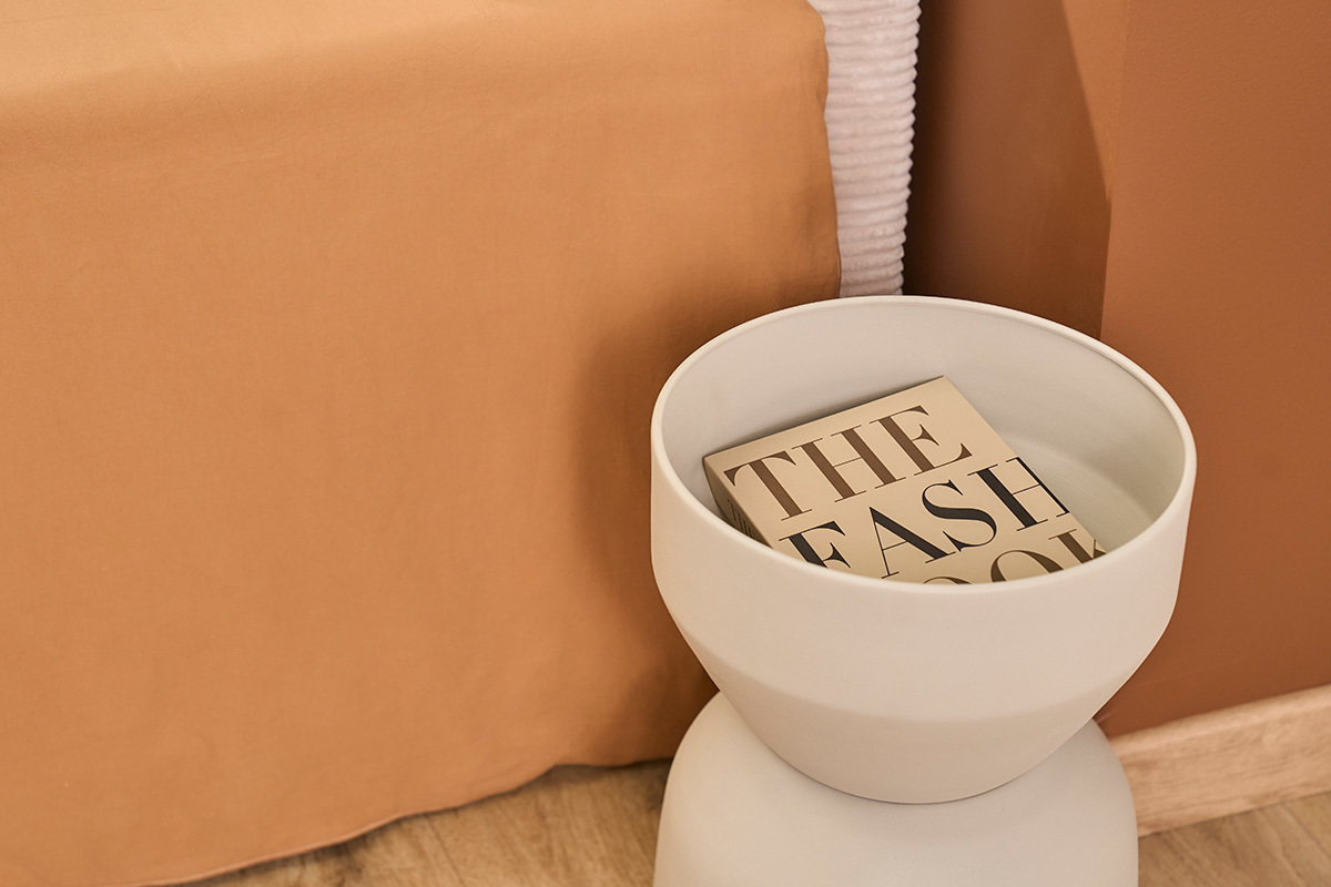 Mesa auxiliar redonda de metal beige con libro, vista desde arriba.