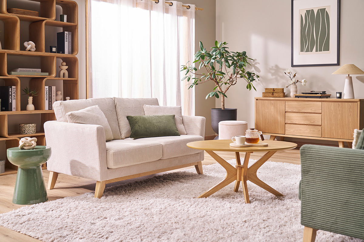 Mesa auxiliar redonda de metal esmaltado en verde caqui en un sal�n con sof� y mesa de centro.