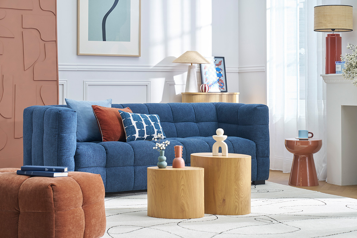 Sal�n con sof� azul, cojines coloridos, mesita auxiliar redonda terracota a la derecha.