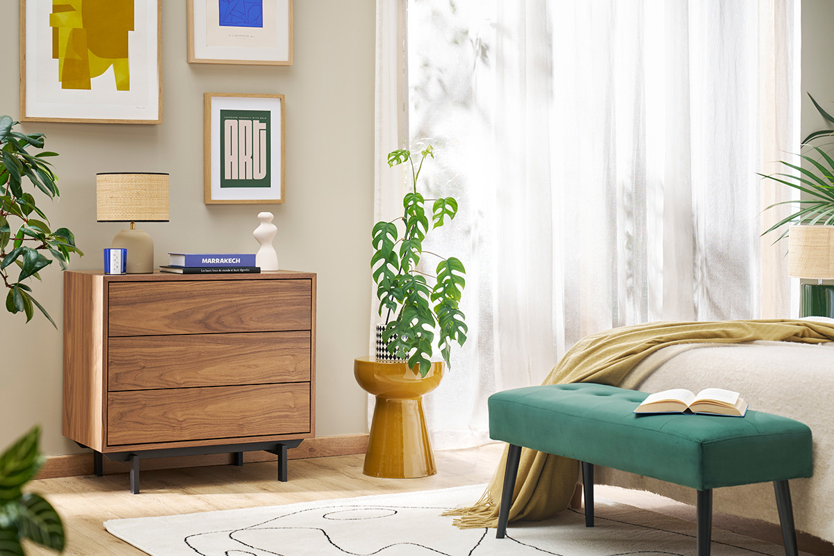 Mesa auxiliar redonda de metal esmaltado en bronce con planta, en habitaci�n luminosa.