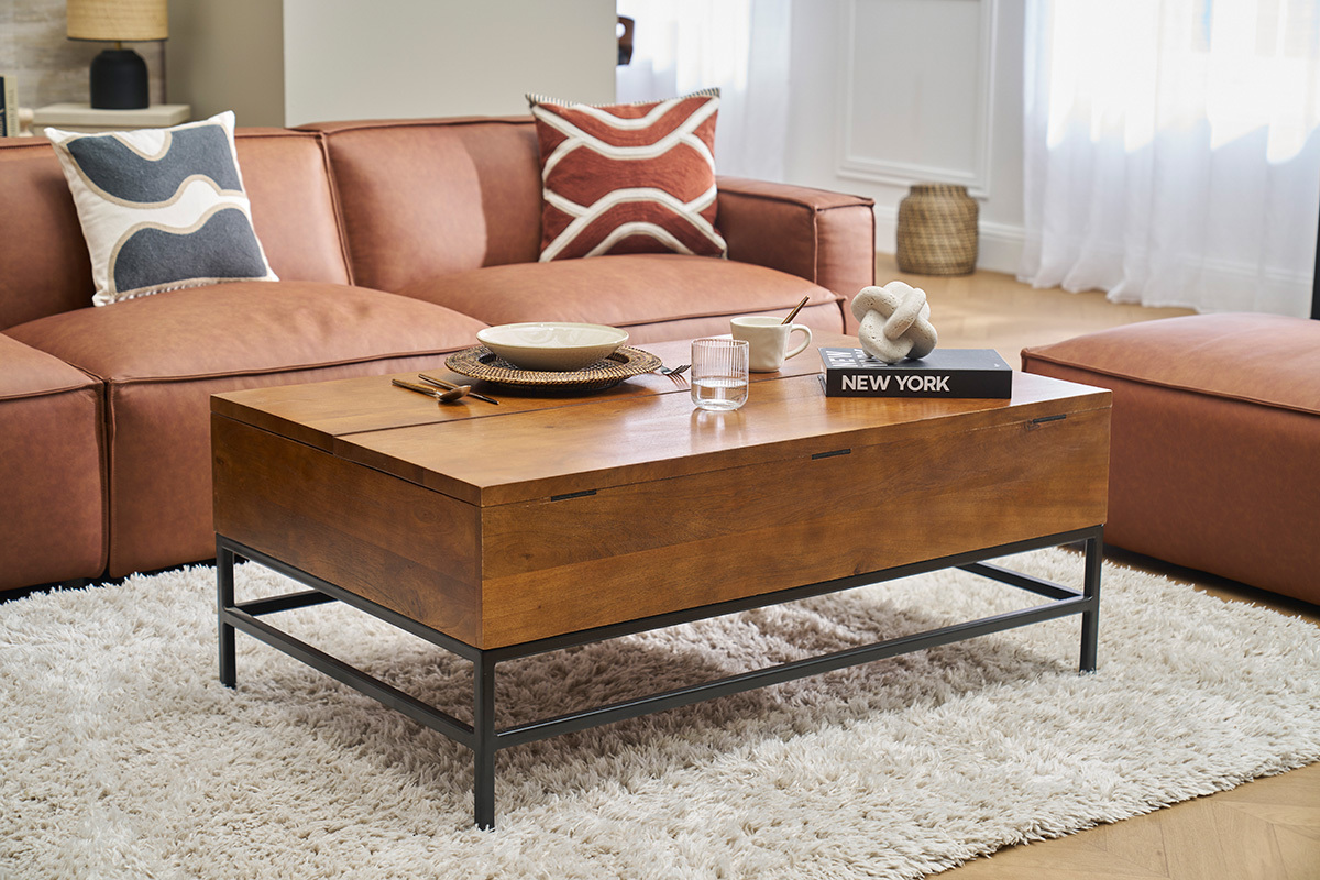 Mesa baja industrial de madera y metal, frente a un sof marrn, vista de 3/4, en un saln.