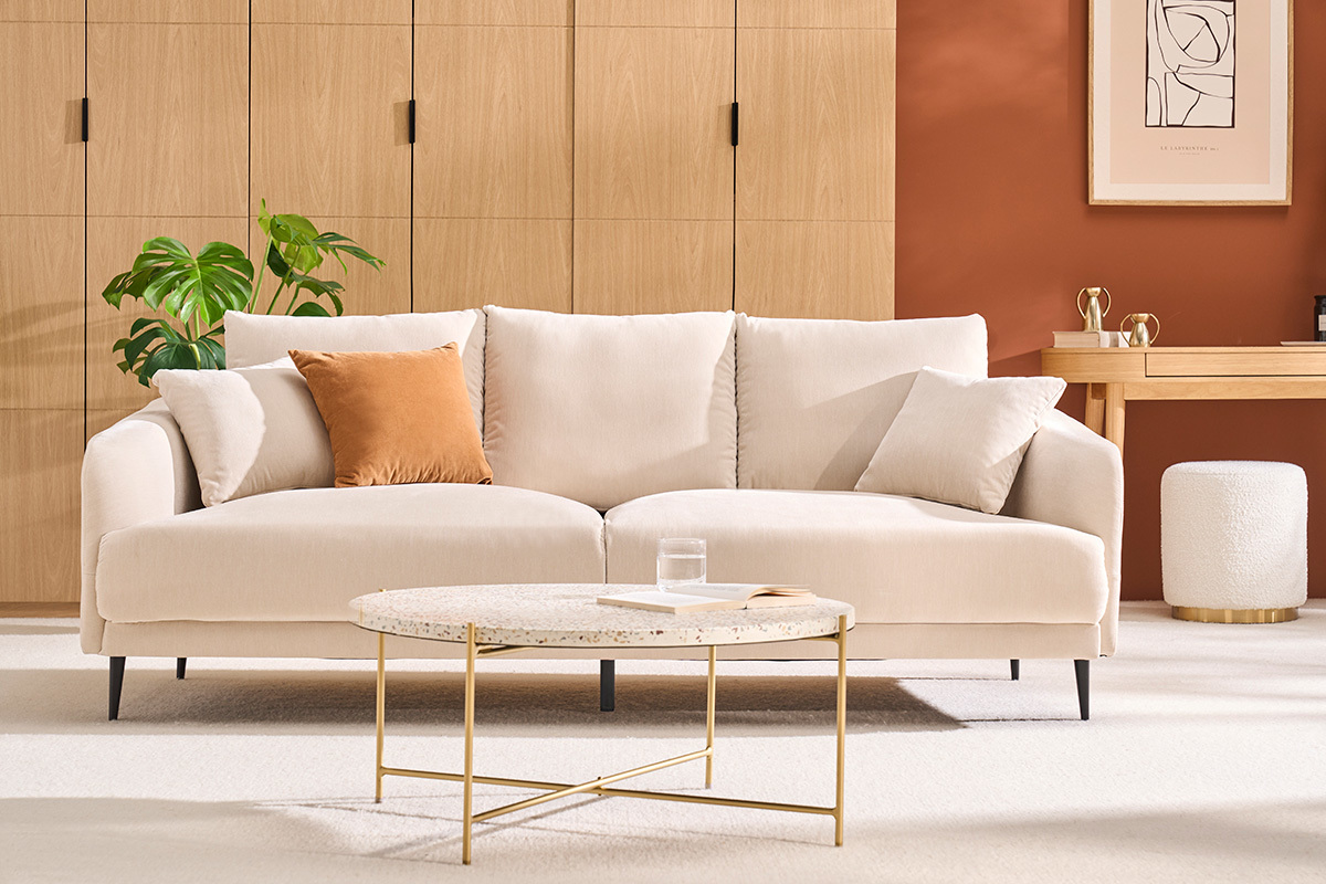 Mesa de centro redonda en terrazo y metal, vista de frente, con sof� y decoraci�n en una sala de estar moderna.