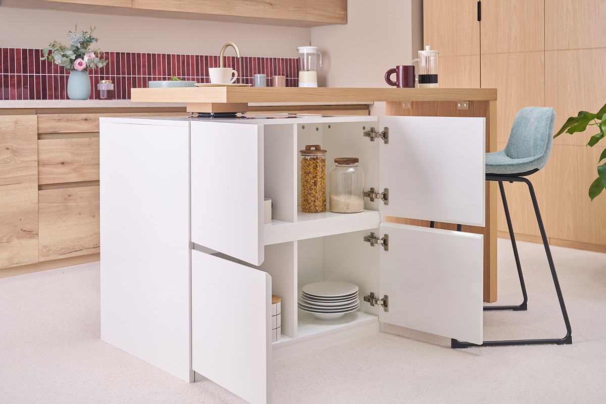 Isla blanca mate con encimera de roble, puertas abiertas mostrando el almacenamiento, taburete azul al lado.