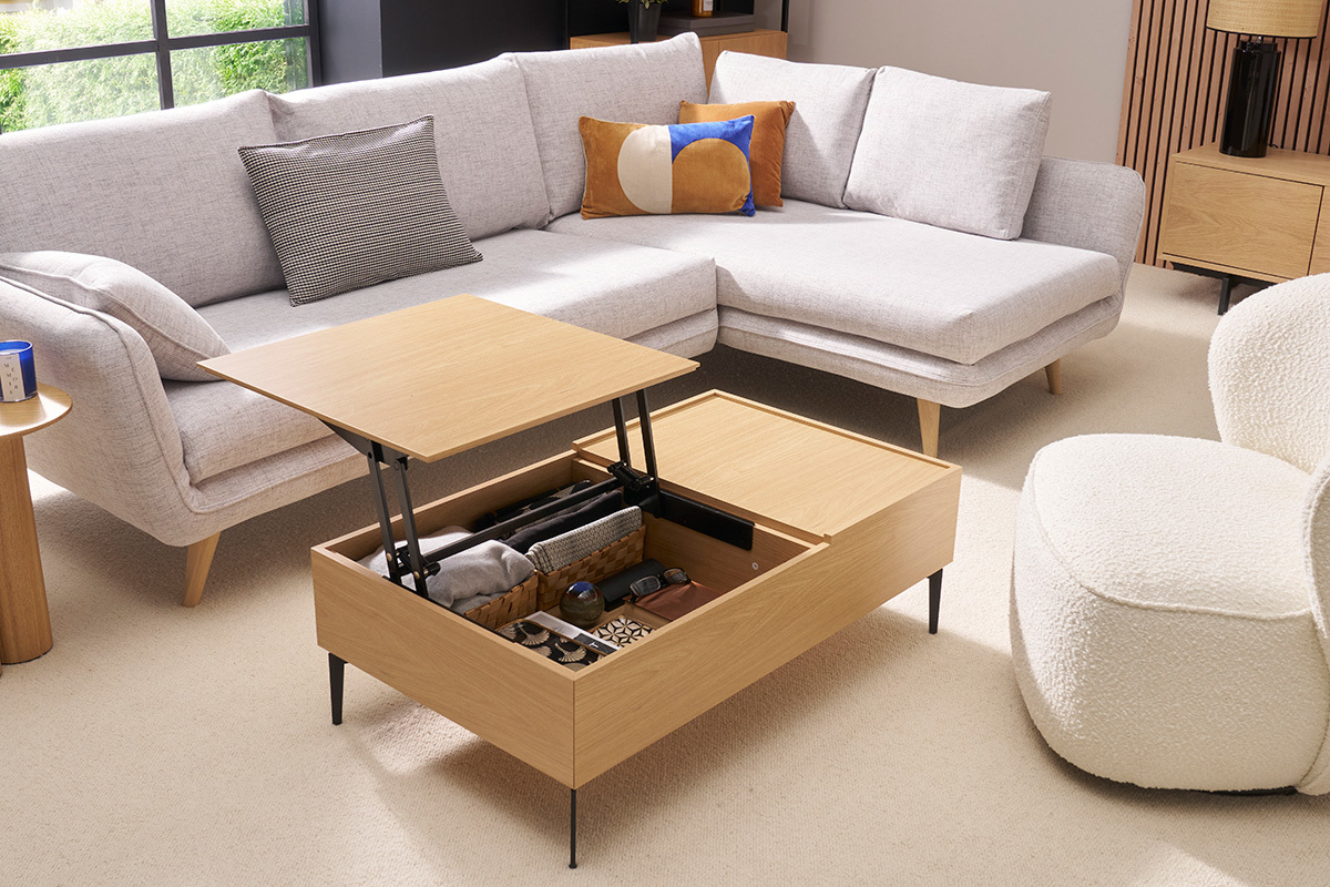 Mesa baja elevable de madera clara con bandeja abierta, almacenamiento visible, en un saln moderno.