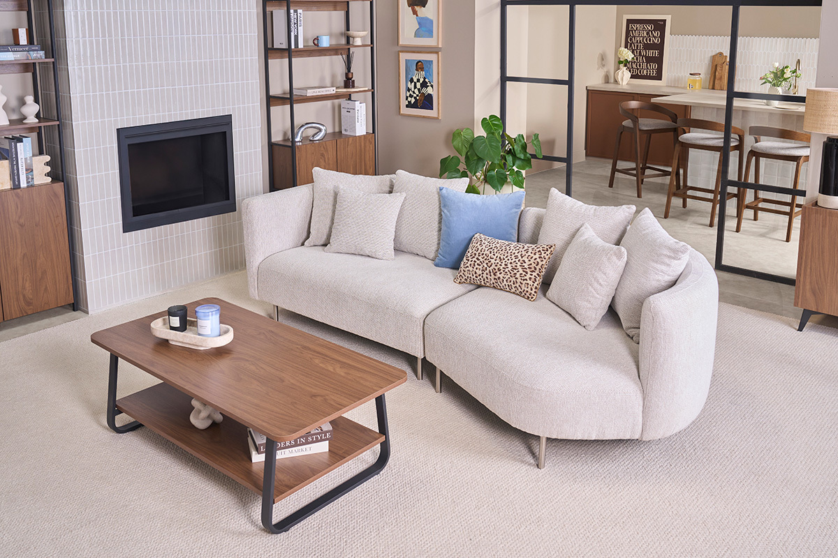 Mesa de centro rectangular de madera de nogal y metal, vista lateral, con sof� y elementos decorativos.