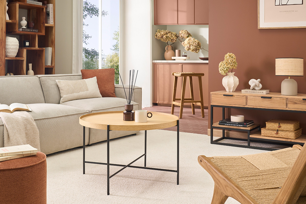 Mesa baja redonda de madera clara y metal negro en un sal�n moderno.