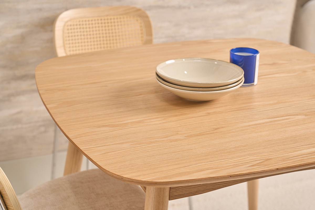 Mesa de comedor escandinava cuadrada de fresno natural con platos apilados, vista en primer plano