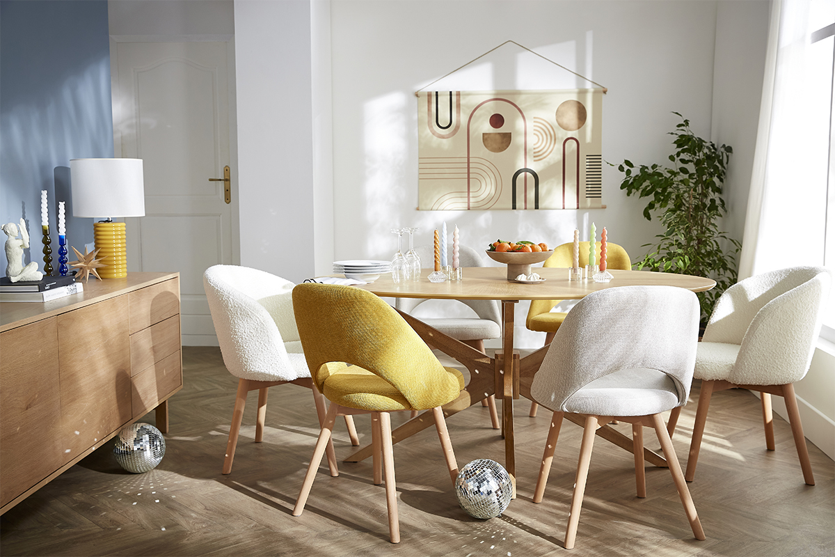 Mesa de comedor ovalada de nogal con sillas coloridas en un comedor luminoso.