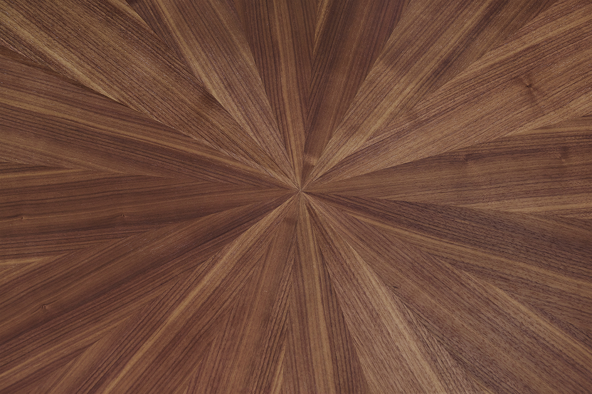 Primer plano de la bandeja ovalada en chapa de nogal con motivo de sol de la mesa DIELLI.