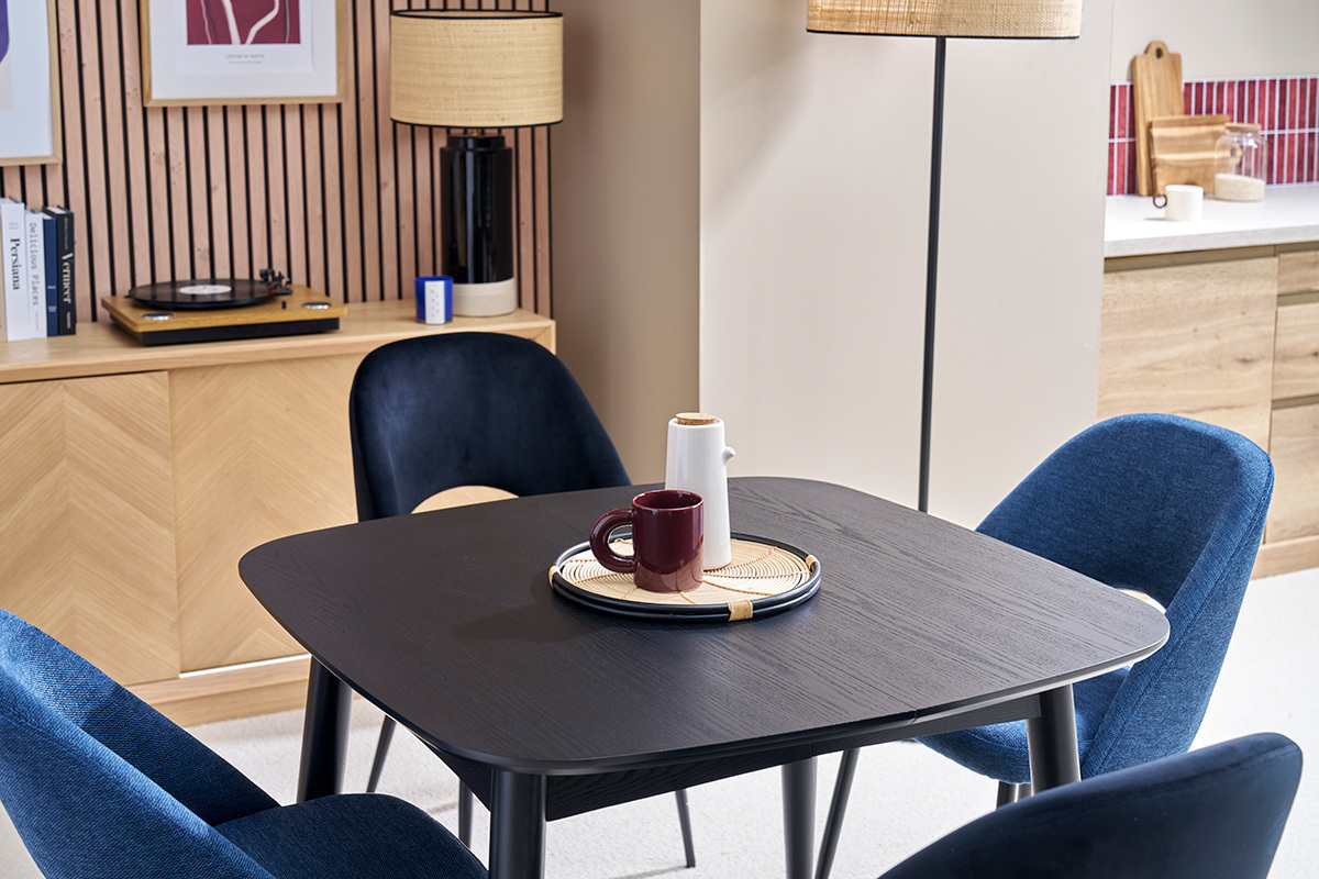 Mesa de comedor extensible NORDECO negra con sillas azules, vista angular.