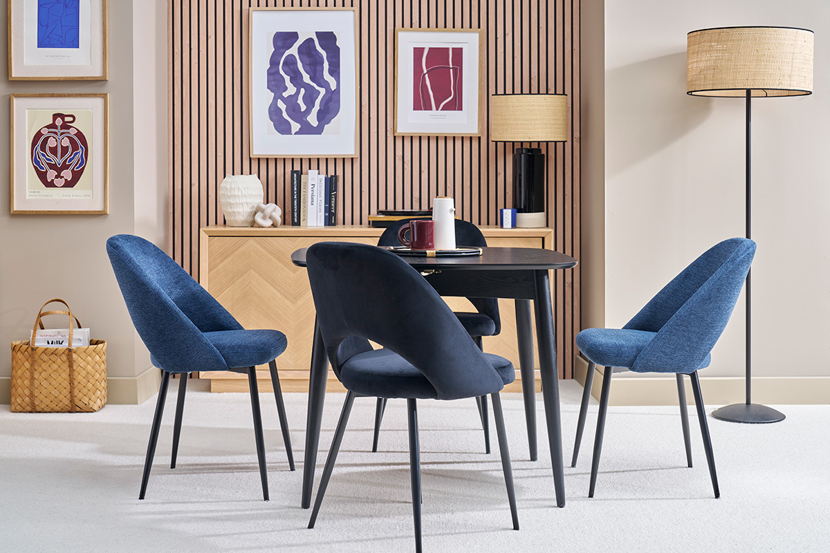 Mesa de comedor extensible negra con sillas azules en un interior moderno.