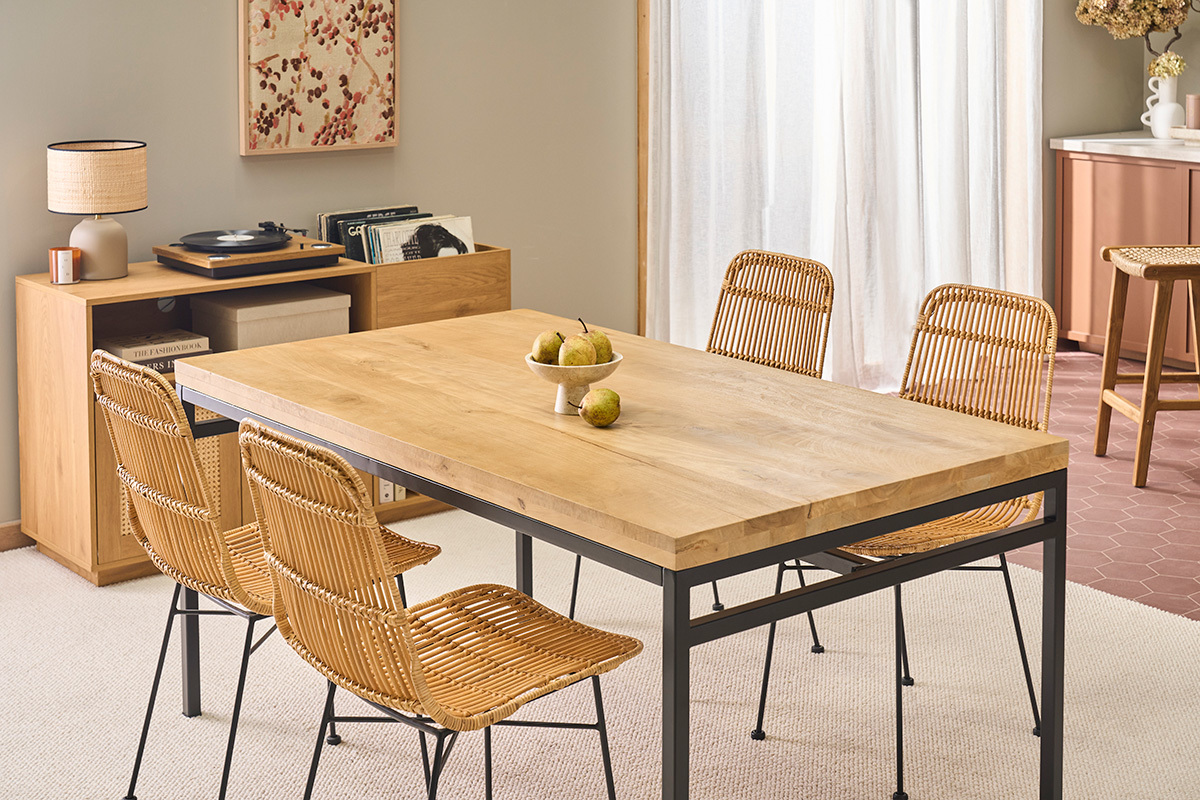 Mesa de comedor industrial de madera y metal con sillas de rat�n, vista angular.