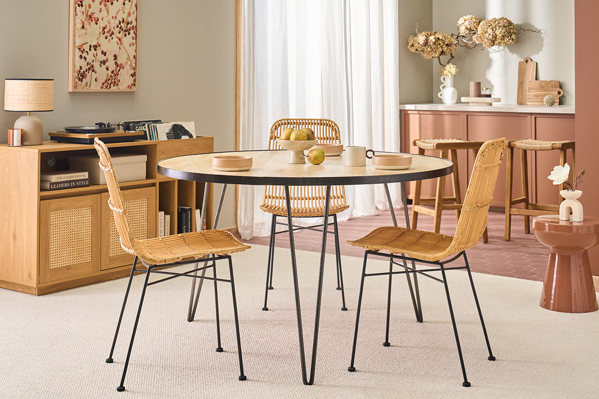 Mesa redonda de madera de mango con patas de metal en un interior con sillas a juego.
