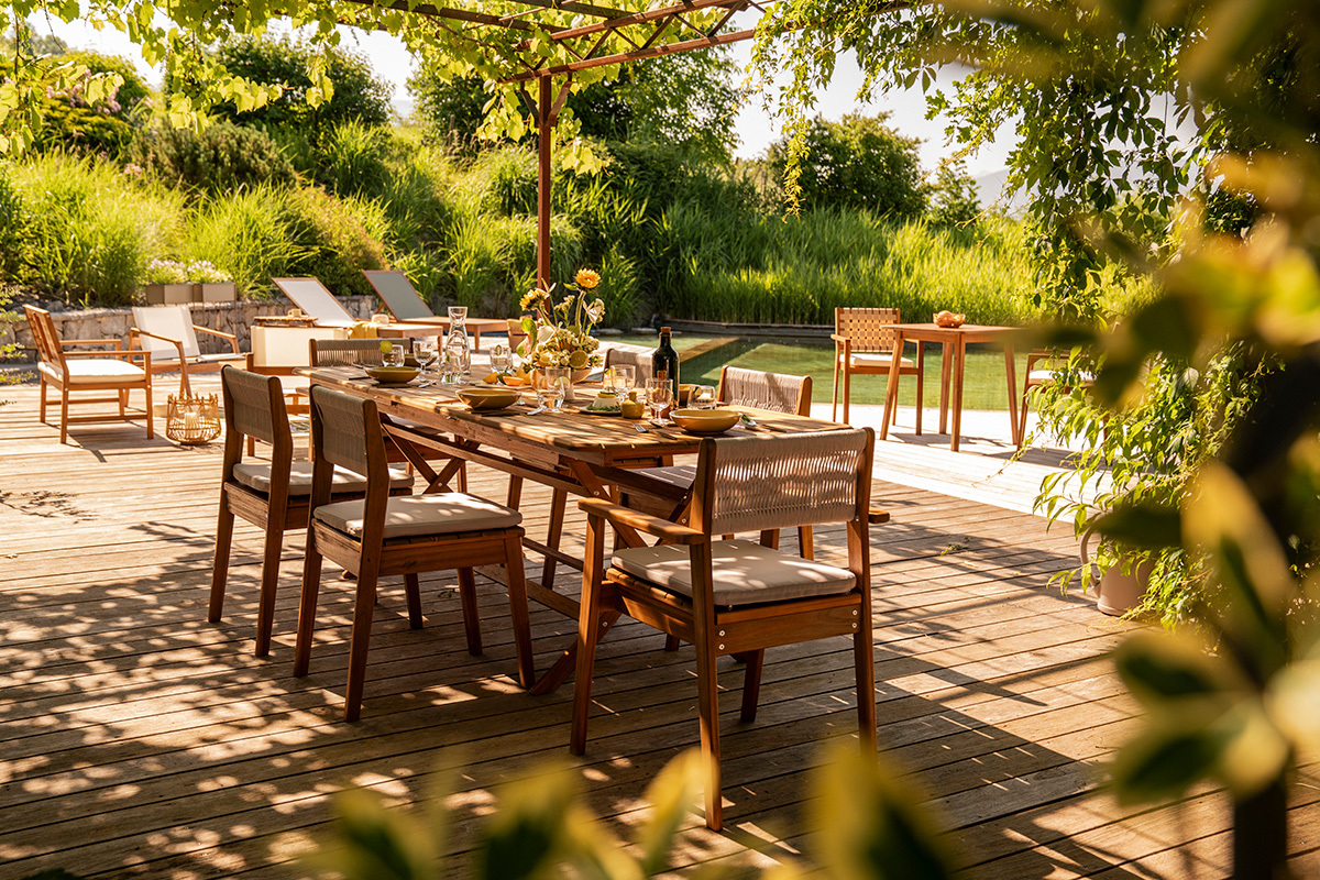 Mesa de jard�n extensible de madera maciza con sillas, vista parcial de una terraza soleada