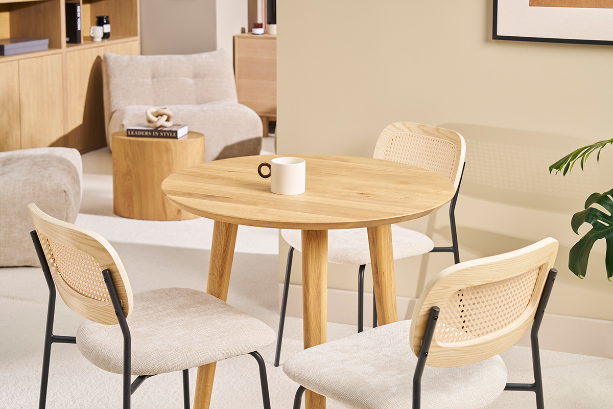 Mesa redonda de madera clara con sillas, vista general en un interior moderno.