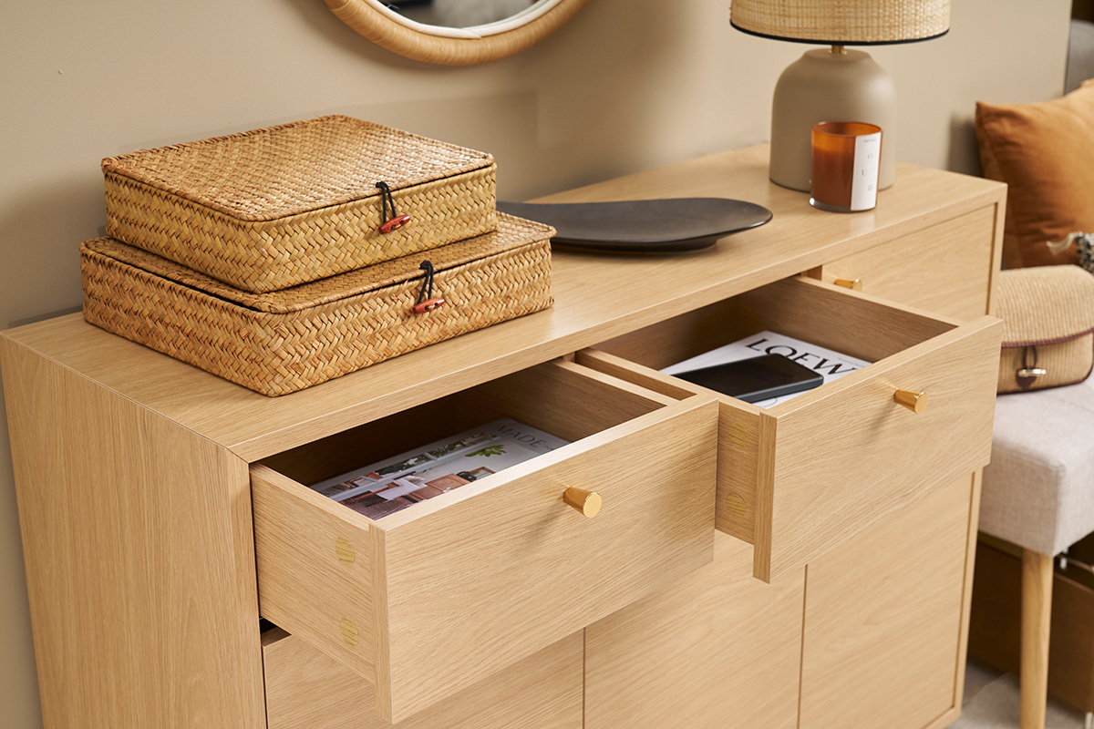 Mueble de entrada de madera clara con cajones abiertos y objetos encima, vista de 3/4.