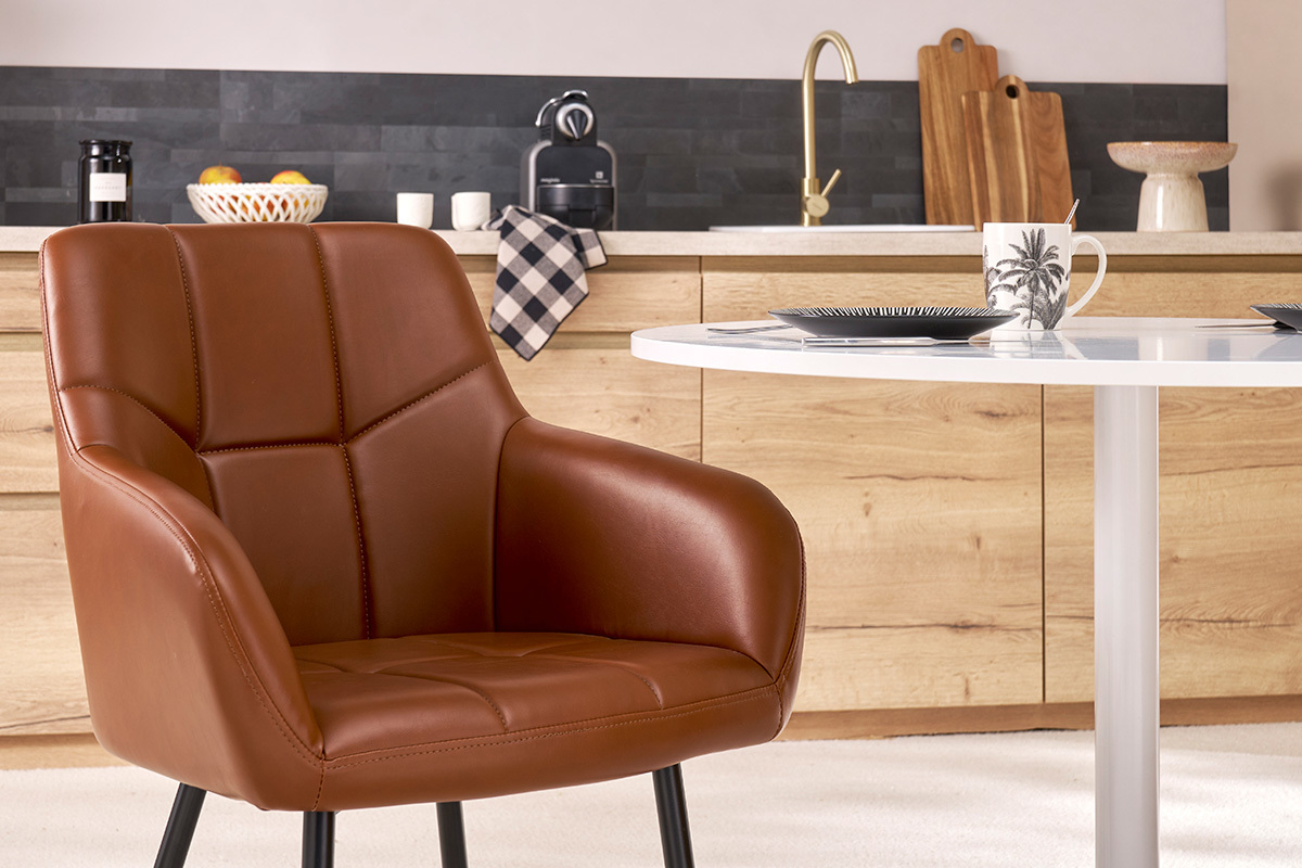 Silla acolchada marrn MONTERO frente a una mesa redonda blanca.