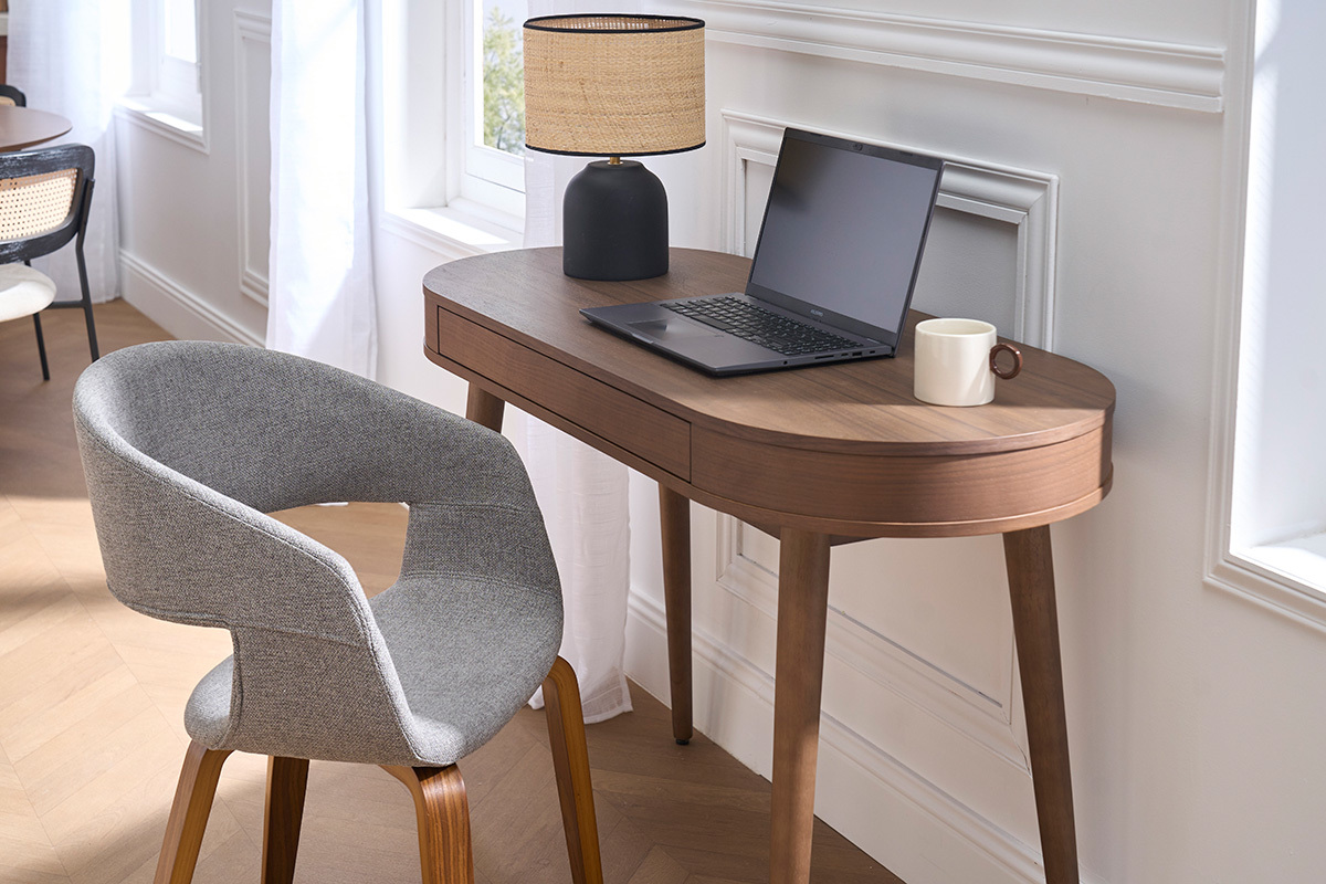 Silla de dise�o en tela gris con patas de madera oscura, vista lateral junto a un escritorio.