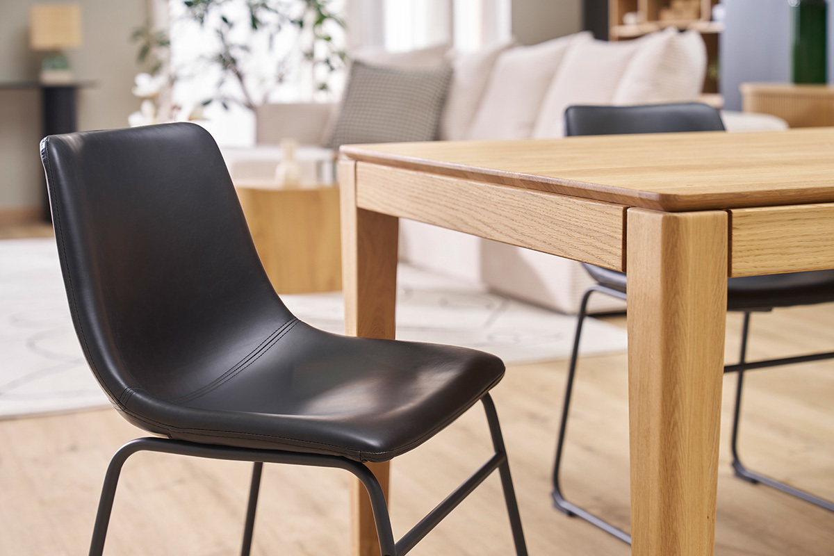 Silla industrial negra NEW ROCK frente a una mesa de madera en un interior moderno.