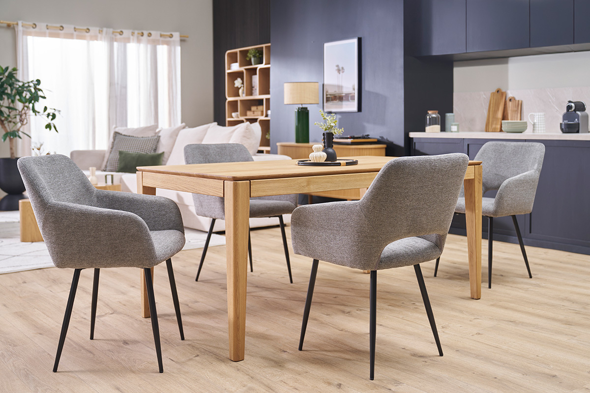 Cuatro sillas LAURETTE de tela efecto terciopelo gris y metal negro alrededor de una mesa de madera en un saln.