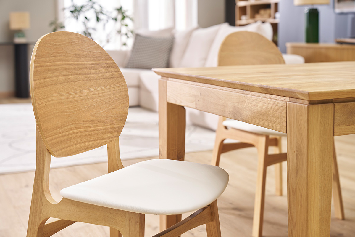 Sillas escandinavas de madera clara y asiento blanco con mesa de madera clara.