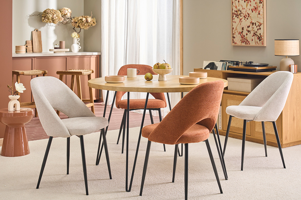 Sillas beige de tela efecto terciopelo, patas de metal negro, alrededor de una mesa redonda.