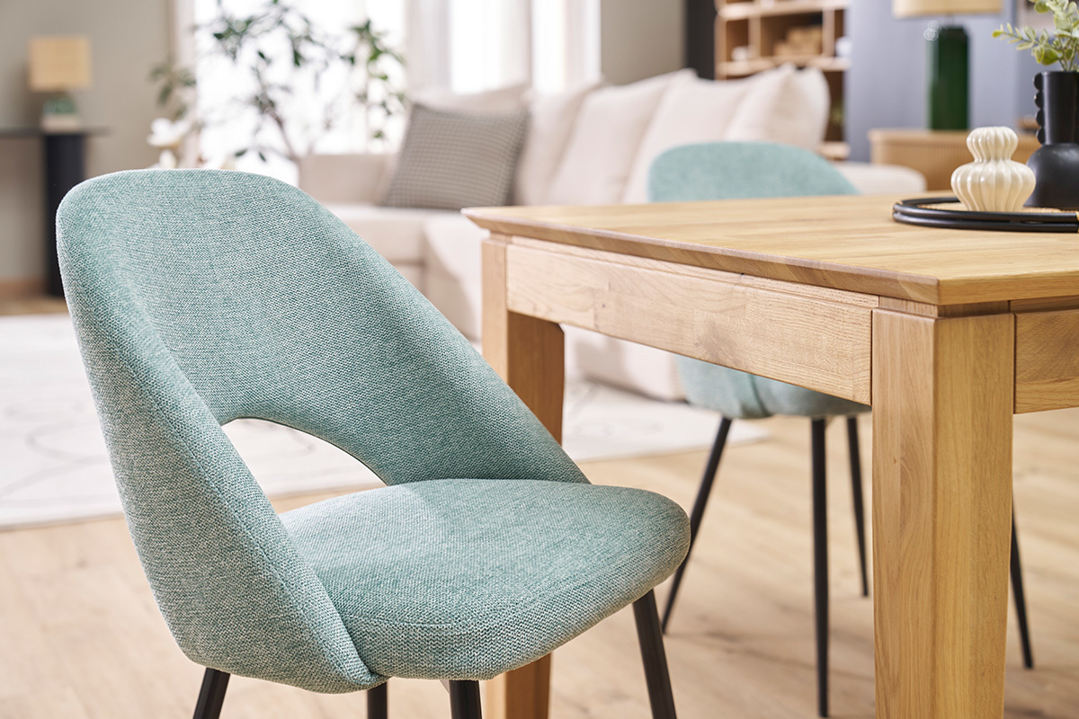 Sillas vintage verde celadn con patas negras, cerca de una mesa de madera, en un saln moderno.