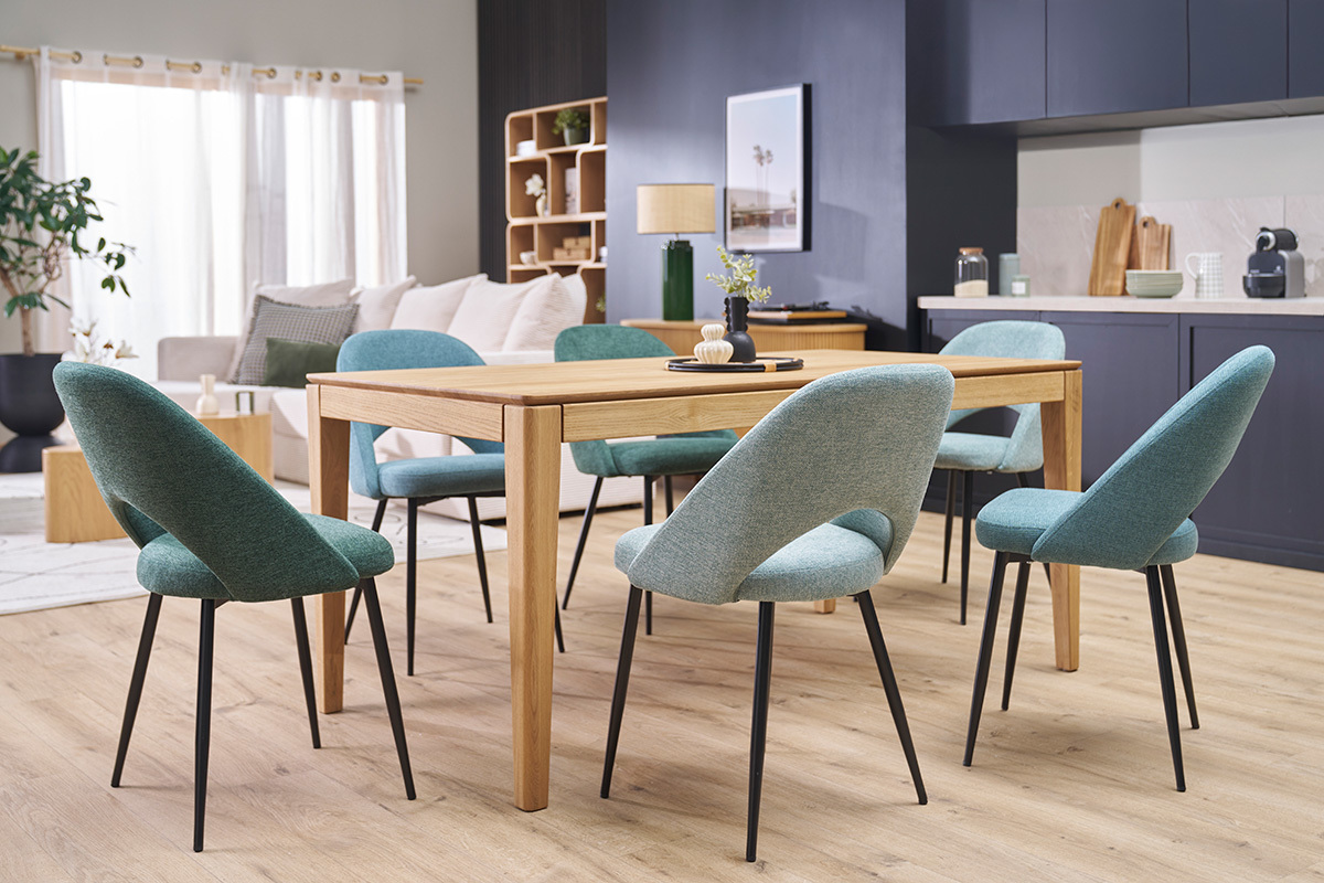 Sillas vintage verde grisceo alrededor de una mesa de madera, patas de metal negro, vista general.