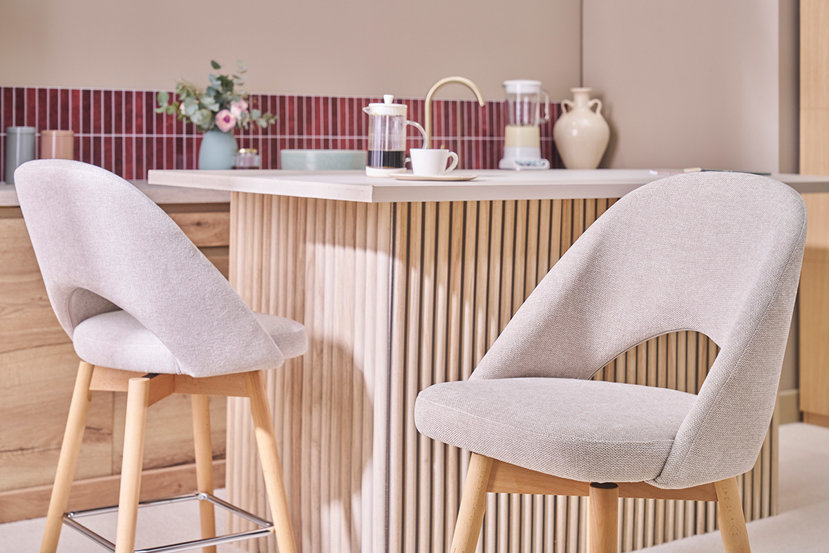 Taburetes de bar escandinavos beige con patas de caucho, frente a un mostrador de cocina.