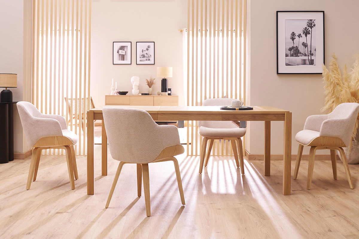 Comedor con cuatro sillas EARL de tela de chenilla gris y patas de madera clara alrededor de una mesa de madera.