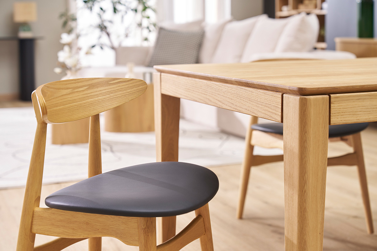 Sillas WALFORD de madera clara y negra alrededor de una mesa de madera clara, vista lateral.