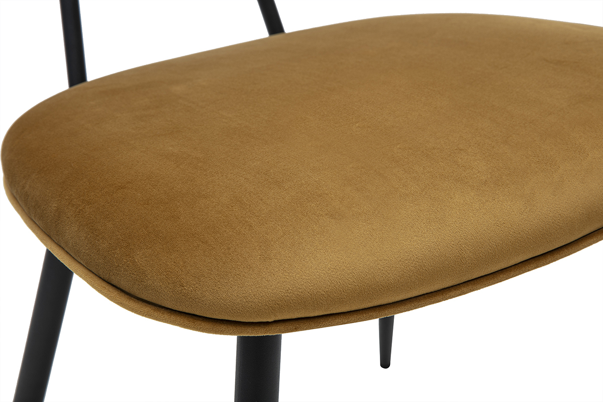 Detalle de una silla de terciopelo bronce con patas de metal negro.