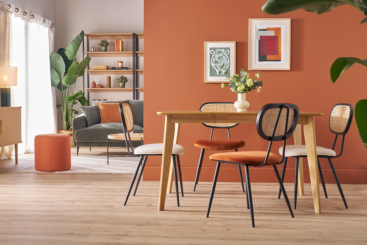 Sillas de dise�o en terciopelo color tierra quemada y rat�n alrededor de una mesa de madera clara.