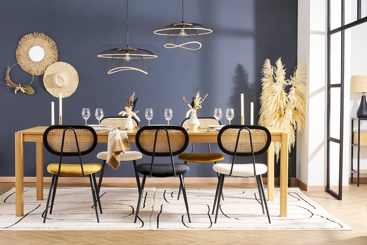 Comedor con sillas SWANN de terciopelo y mimbre, alrededor de una mesa de madera.