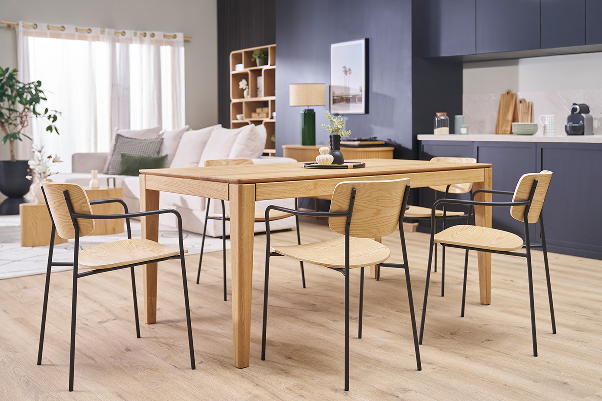 Sillas de madera clara y metal negro alrededor de una mesa de madera en un interior moderno.