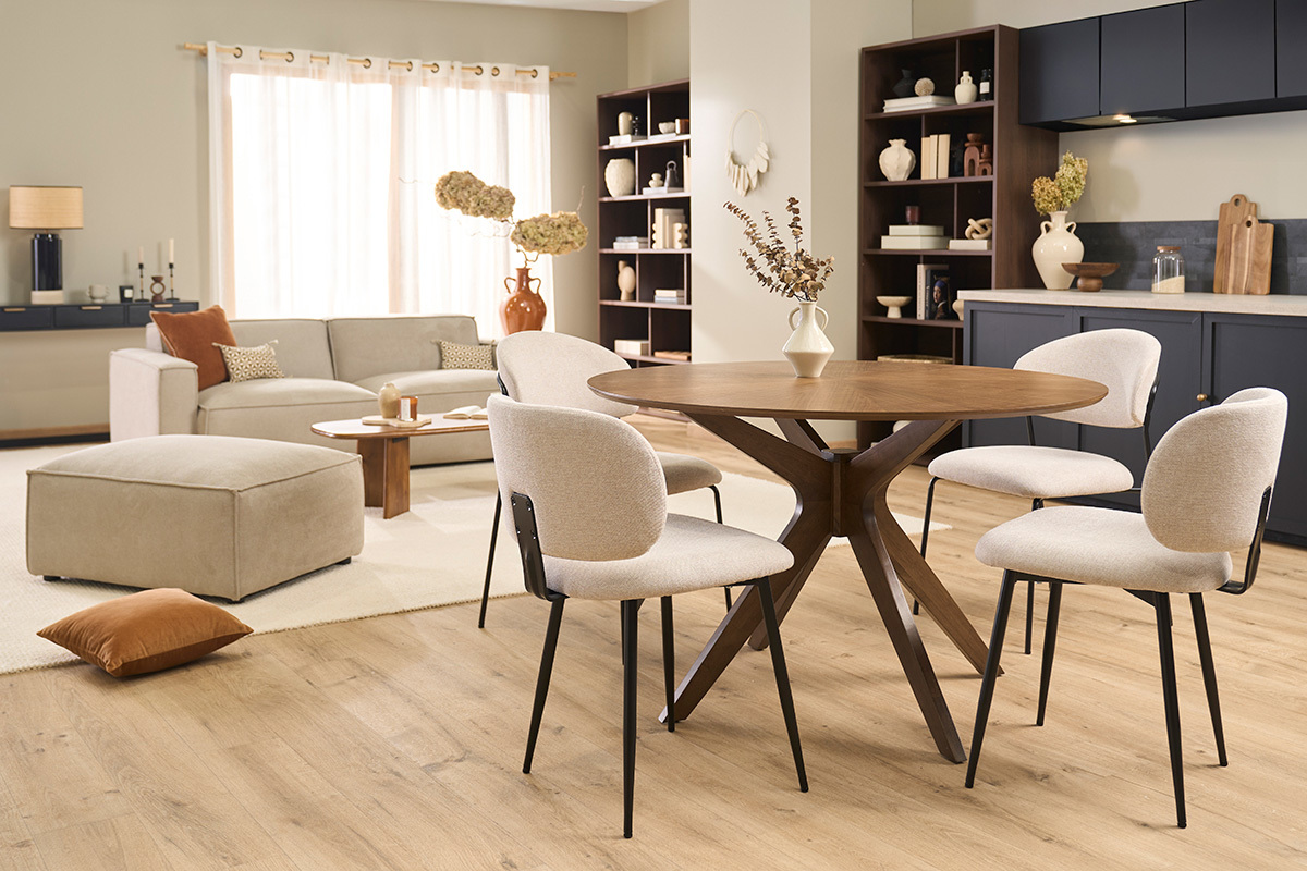 Sillas beige de tela efecto terciopelo y metal negro alrededor de una mesa redonda de madera.