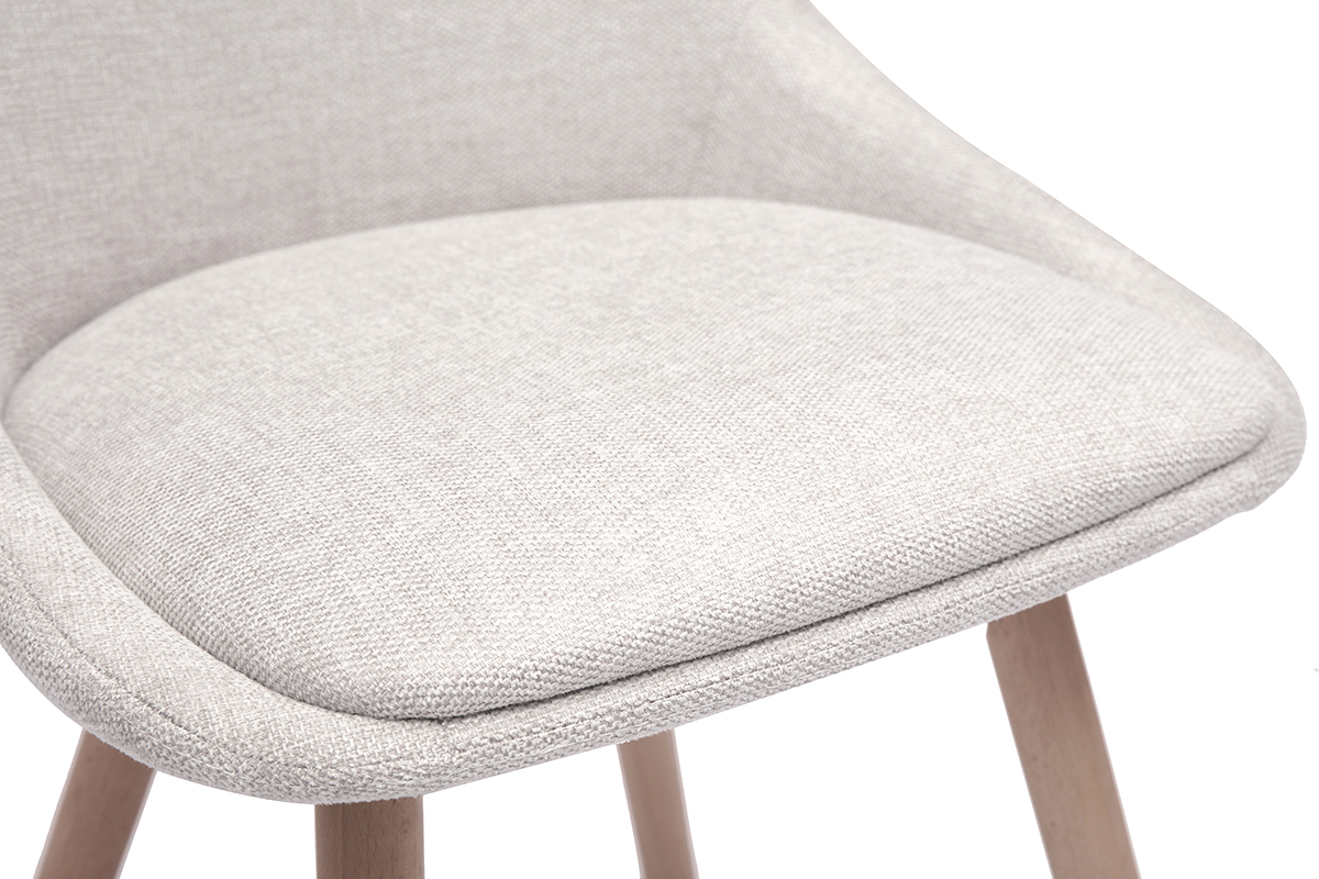 Primer plano del asiento acolchado de una silla de tela efecto terciopelo beige y patas de madera clara.