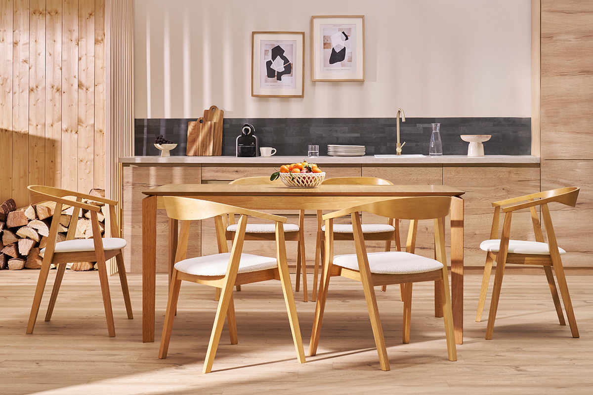 Sillas escandinavas BAHIA de madera clara y asiento blanco alrededor de una mesa de comedor en un interior moderno.