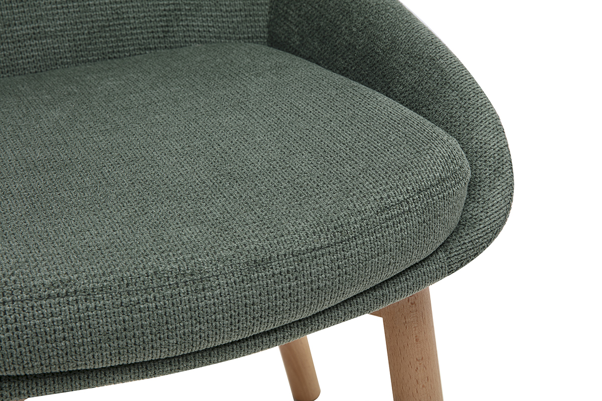 Detalle del asiento de una silla escandinava en tejido de chenilla verde caqui con patas de madera clara.