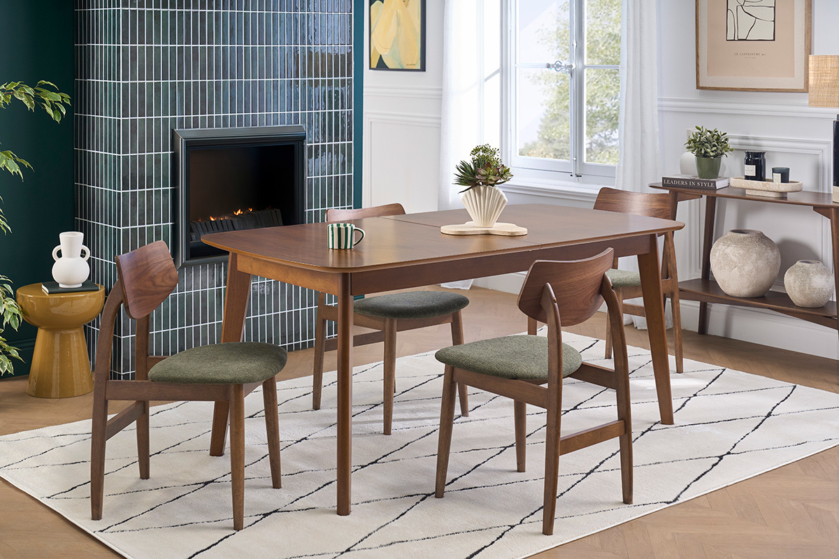 Sillas escandinavas de madera oscura y tela de terciopelo verde caqui alrededor de una mesa en un interior moderno