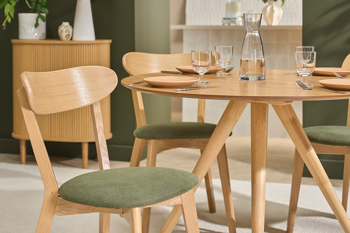 Sillas vintage DOVE de madera clara con asiento de tela verde caqui, vista junto a una mesa redonda.